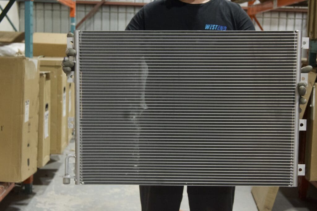 Shop tech holding an A/C condenser